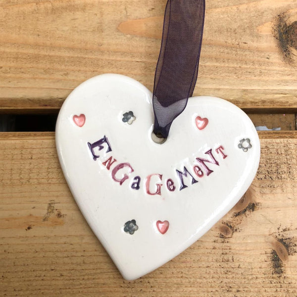 Hand painted ceramic heart featuring hearts and flowers design and the sentiment 'Engagement'  Handmade in the UK using clay, glaze and paint sourced locally.