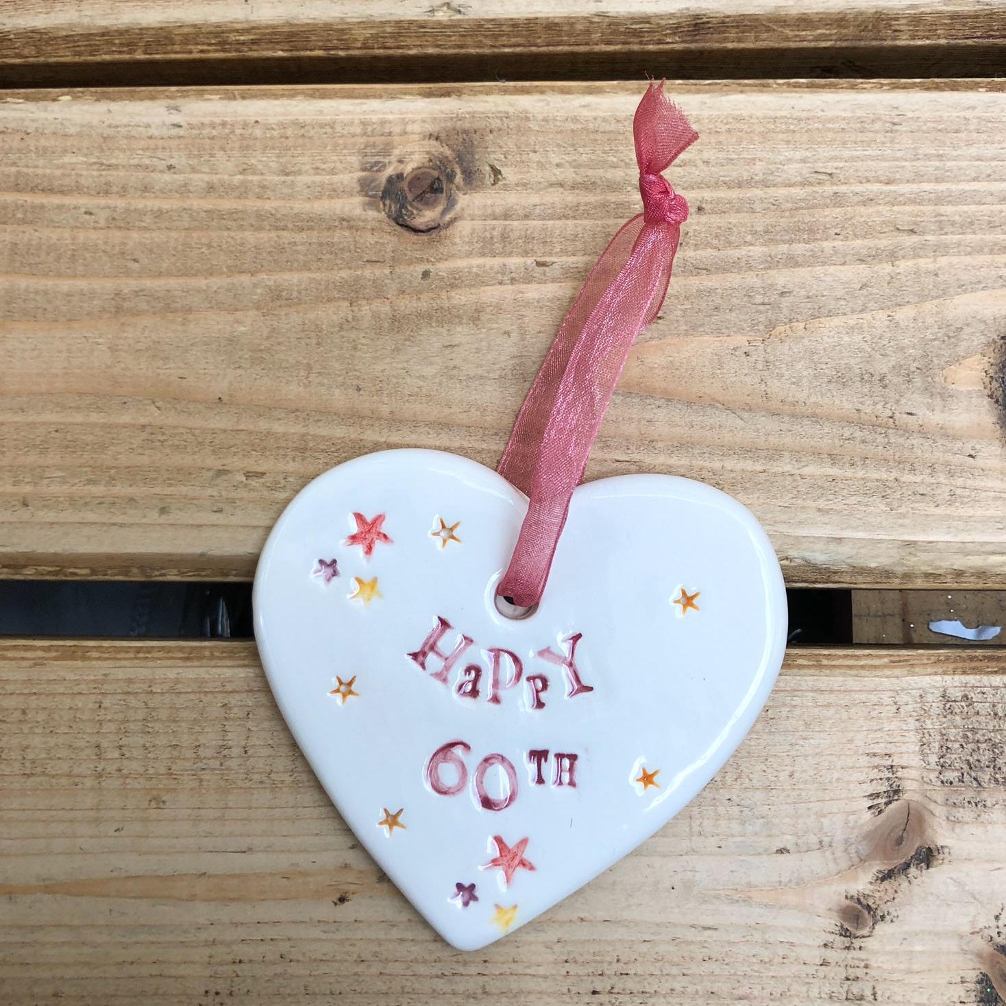Hand painted ceramic heart featuring star design and the sentiment 'Happy 60th' Handmade in the UK using clay, glaze and paint sourced locally. Material: Ceramic