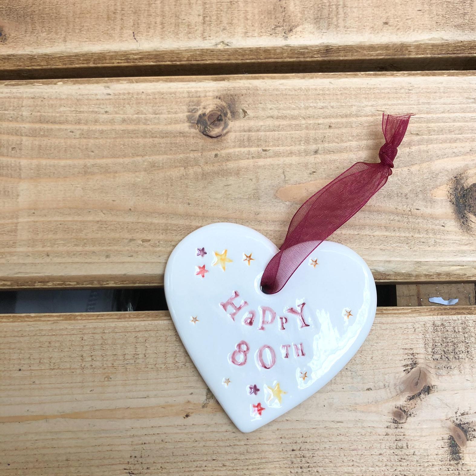 Hand painted ceramic heart featuring star design and the sentiment 'Happy 80th' Handmade in the UK using clay, glaze and paint sourced locally. Material: Ceramic