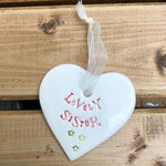 Hand painted ceramic heart featuring a flower design and the sentiment 'Lovely Sister'  Handmade in the UK using clay, glaze and paint sourced locally.  Material:  Ceramic