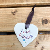 Hand painted ceramic heart featuring a flower design and the sentiment 'Lovely Daughter' Handmade in the UK using clay, glaze and paint sourced locally. Material: Ceramic