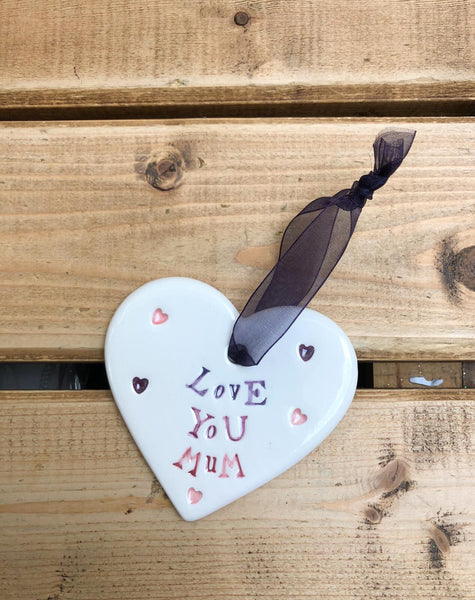Hand painted ceramic heart featuring a flower design and the sentiment 'Love You Mum'  Handmade in the UK using clay, glaze and paint sourced locally.  Material:  Ceramic