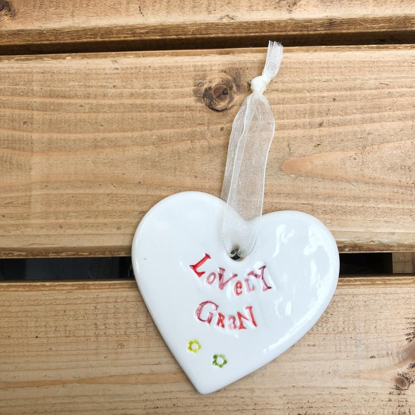 Hand painted ceramic heart featuring a flower design and the sentiment 'Lovely Gran'  Handmade in the UK using clay, glaze and paint sourced locally.  Material:  Ceramic