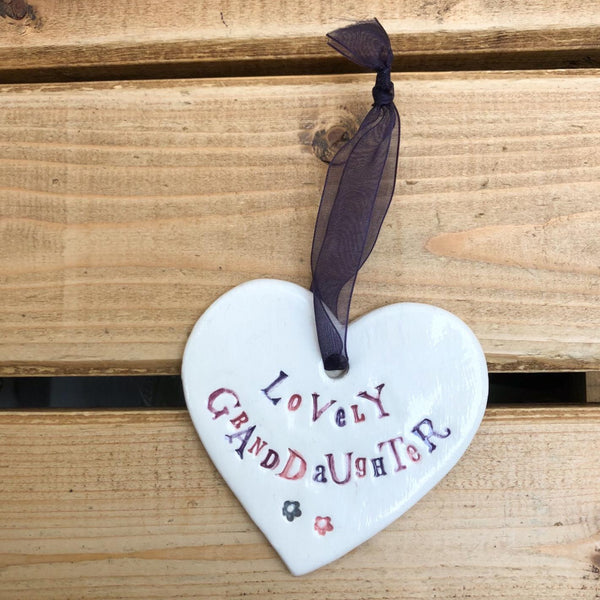 Hand painted ceramic heart featuring a flower design and the sentiment 'Lovely Granddaughter'  Handmade in the UK using clay, glaze and paint sourced locally.  Material:  Ceramic