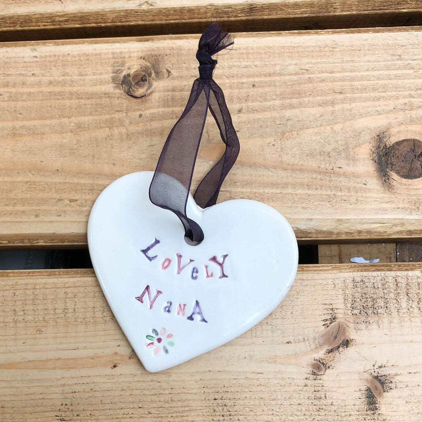 Hand painted ceramic heart featuring a flower design and the sentiment 'Lovely Nana'  Handmade in the UK using clay, glaze and paint sourced locally.  Material:  Ceramic