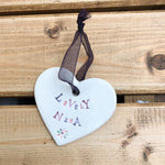 Hand painted ceramic heart featuring a flower design and the sentiment 'Lovely Nana'  Handmade in the UK using clay, glaze and paint sourced locally.  Material:  Ceramic
