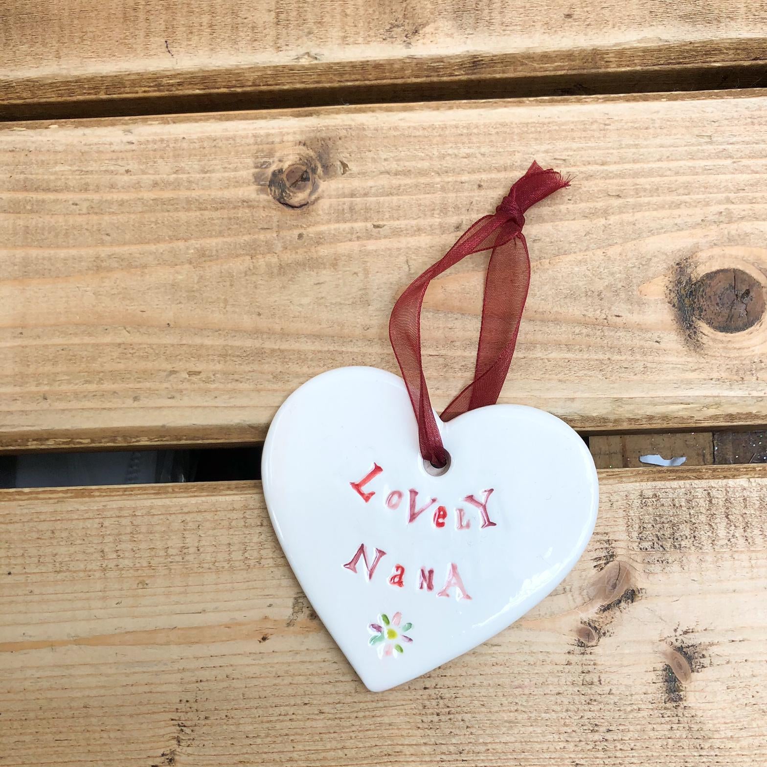 Hand painted ceramic heart featuring a flower design and the sentiment 'Lovely Nana'  Handmade in the UK using clay, glaze and paint sourced locally.  Material:  Ceramic