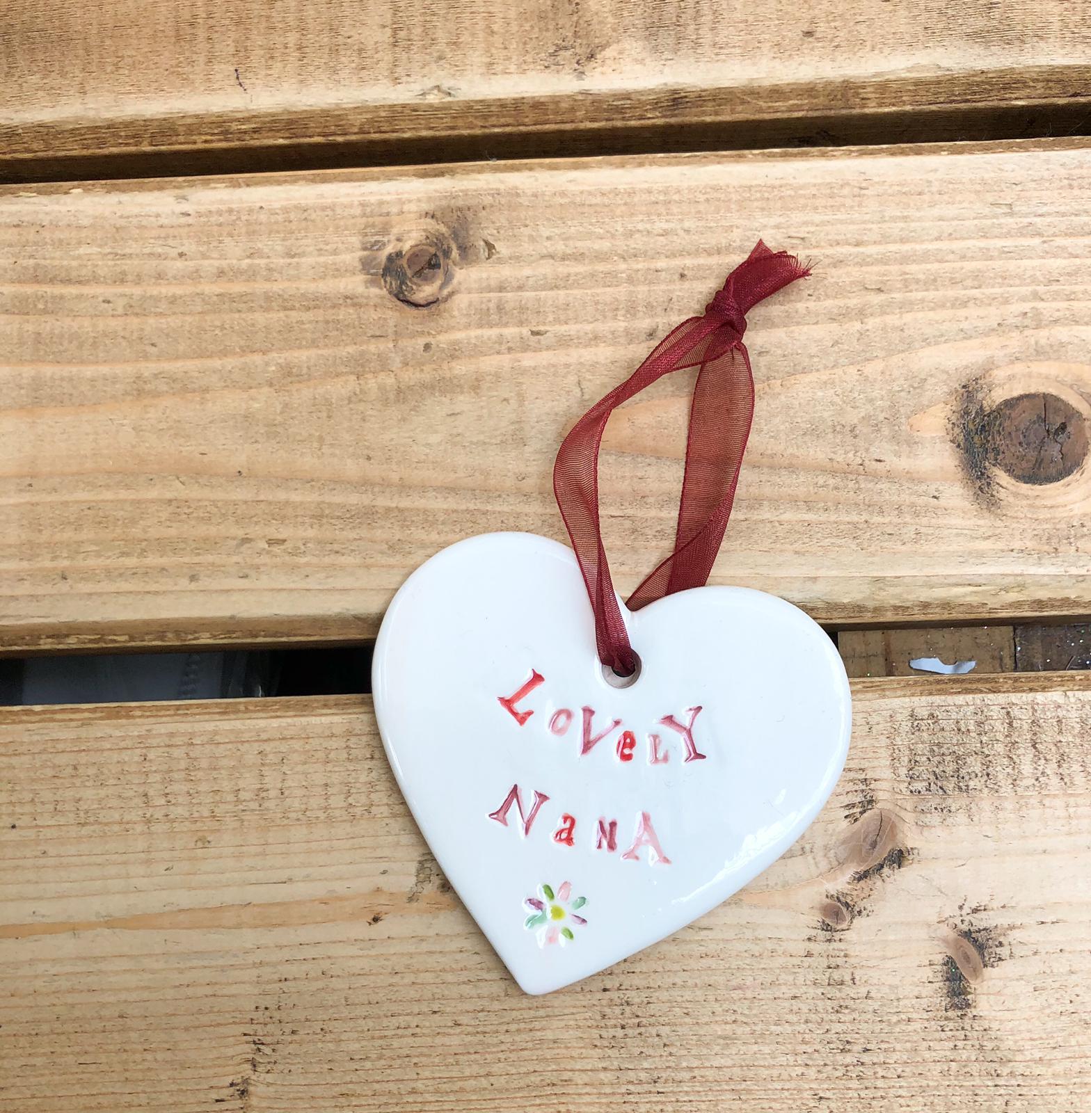 Hand painted ceramic heart featuring a flower design and the sentiment 'Lovely Nana'  Handmade in the UK using clay, glaze and paint sourced locally.  Material:  Ceramic