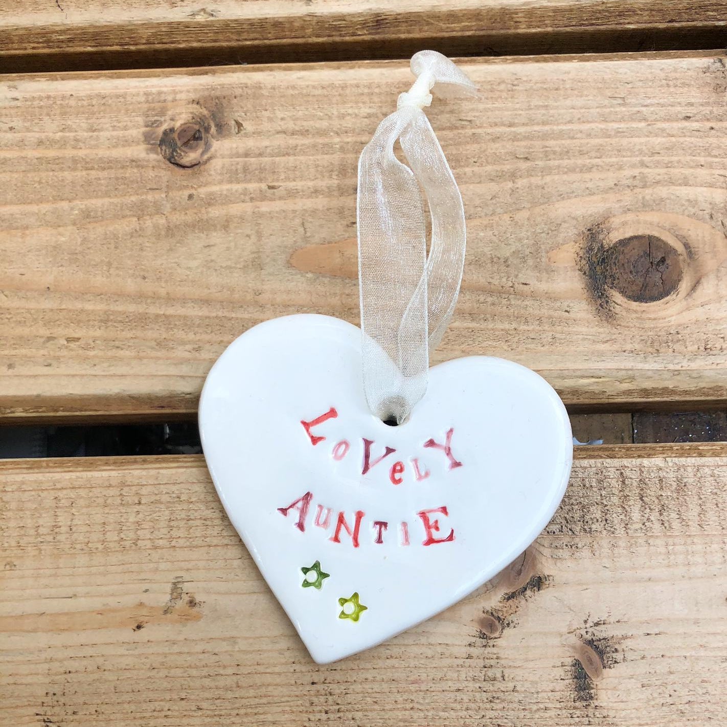 Hand painted ceramic heart featuring a flower design and the sentiment 'Lovely Auntie' Handmade in the UK using clay, glaze and paint sourced locally. Material: Ceram