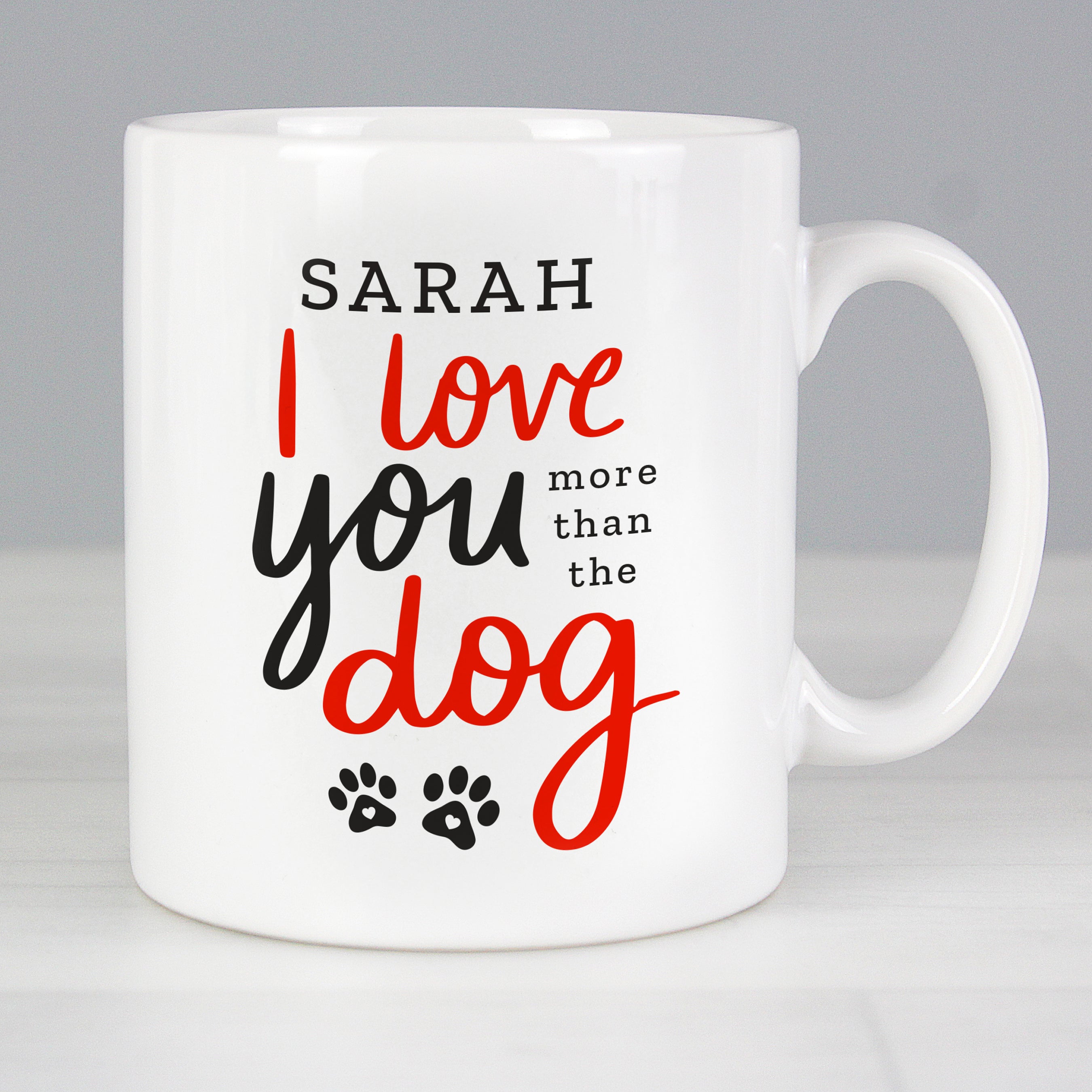 Personalised mug features the text "I love you more than the dog" on the front in red and black text with cute paw print design