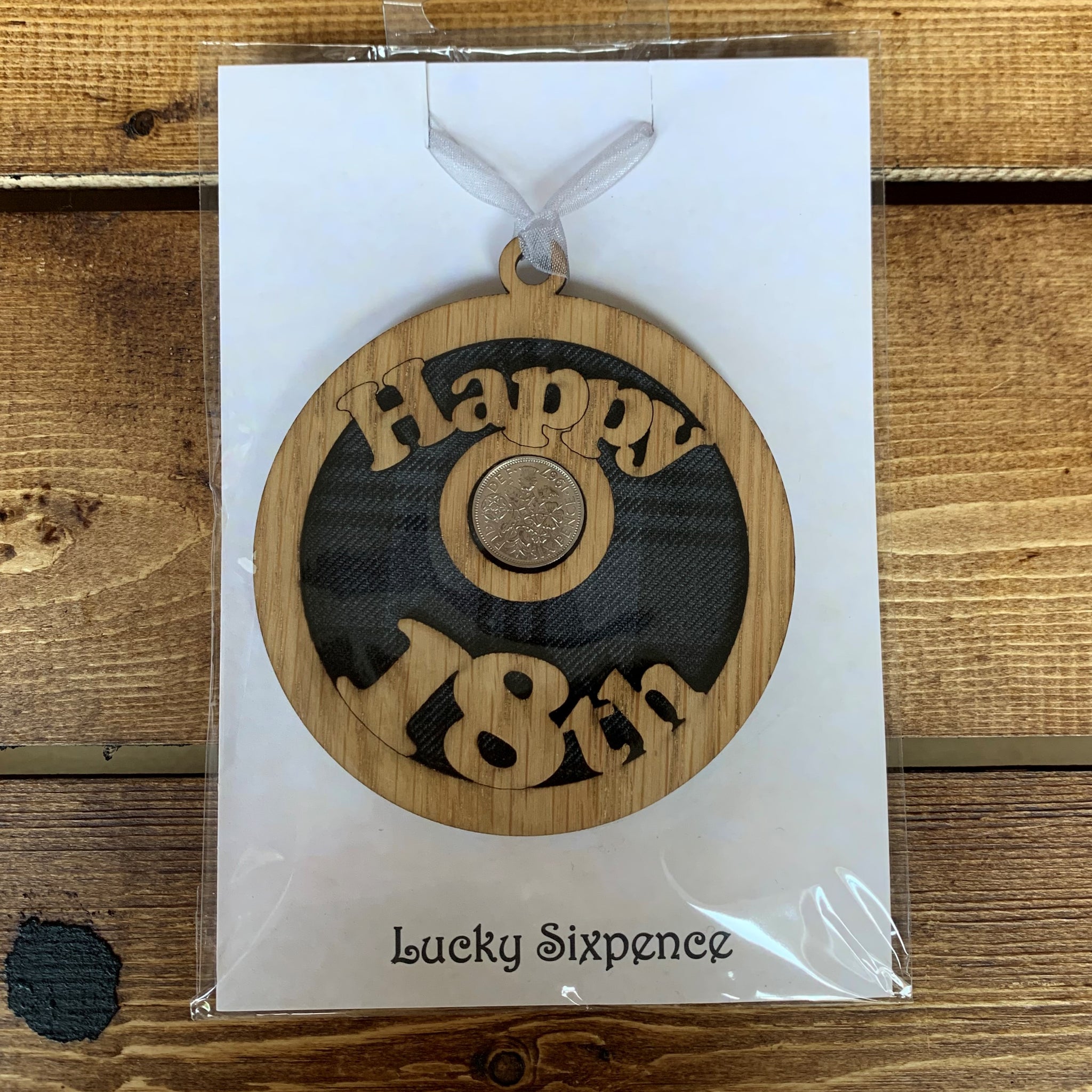 Keepsake gift with a Scottish twist.  The sixpence is mounted onto a round hanging oak veneered wood with tartan inserts, mounted on card and packaged in clear cellophane packets.   'Happy 18th' is cut into the wooden hanging.