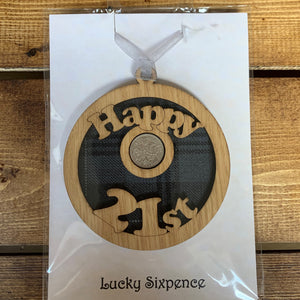 A unique keepsake gift with a Scottish twist.  The sixpence is mounted onto a round hanging oak veneered wood with tartan inserts, mounted on card and packaged in clear cellophane packets.  'Happy 21st' is laser cut into the wooden hanging.