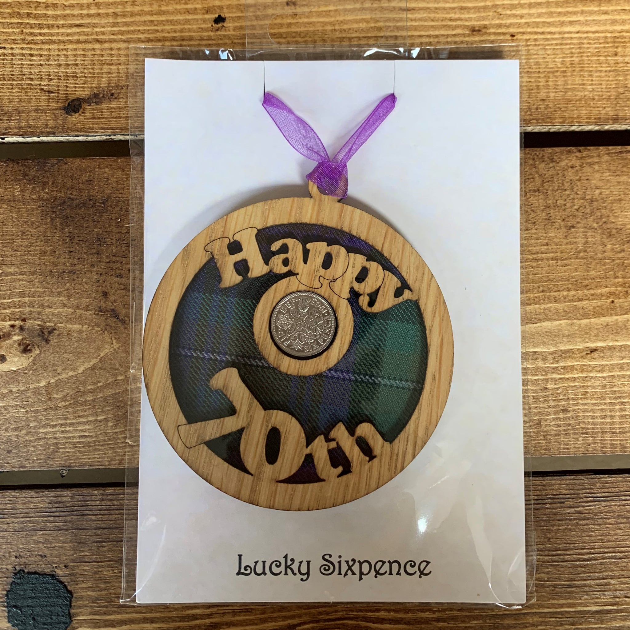 A unique keepsake gift with a Scottish twist.  The sixpence is mounted onto a round hanging oak veneered wood with tartan inserts, mounted on card and packaged in clear cellophane packets.  'Happy 70th' is cut into the wooden hanging.
