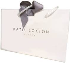 a white gift bag with the words Katie Loxton London in gold foil on the front and a silver/grey ribbon at the top, tied into a bow