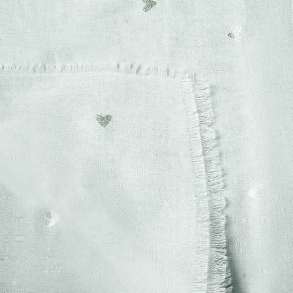 a close up of the edge of a folded scarf, it is a small heart print in a duck egg blue colour with silver details and lightly frayed edges